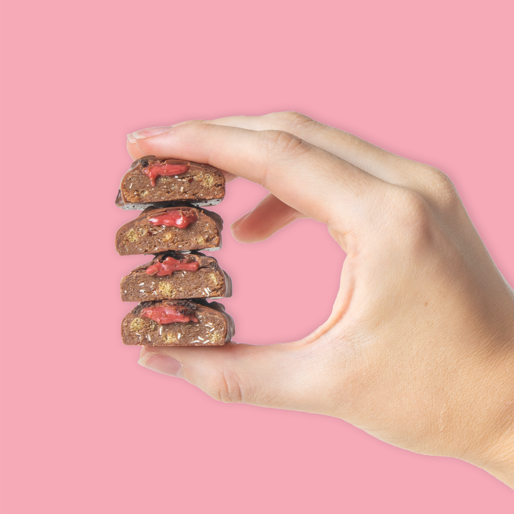 Hand holding stack of Black Forest Gateau Protein Bars with Red Cherry Caramel oozing out