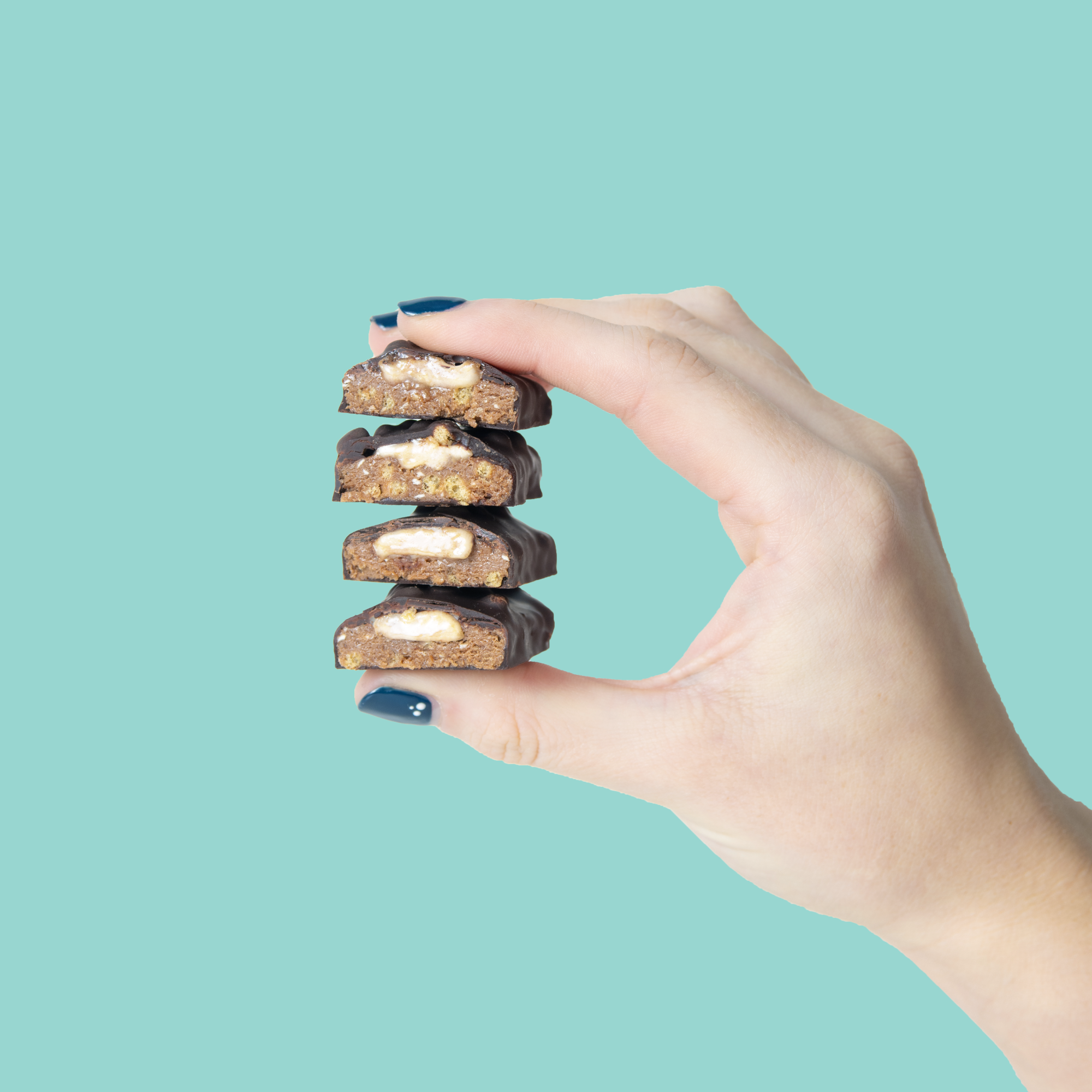 Hand holding a stack of Yubibar mint chocolate protein bars with white mint caramel oozing out